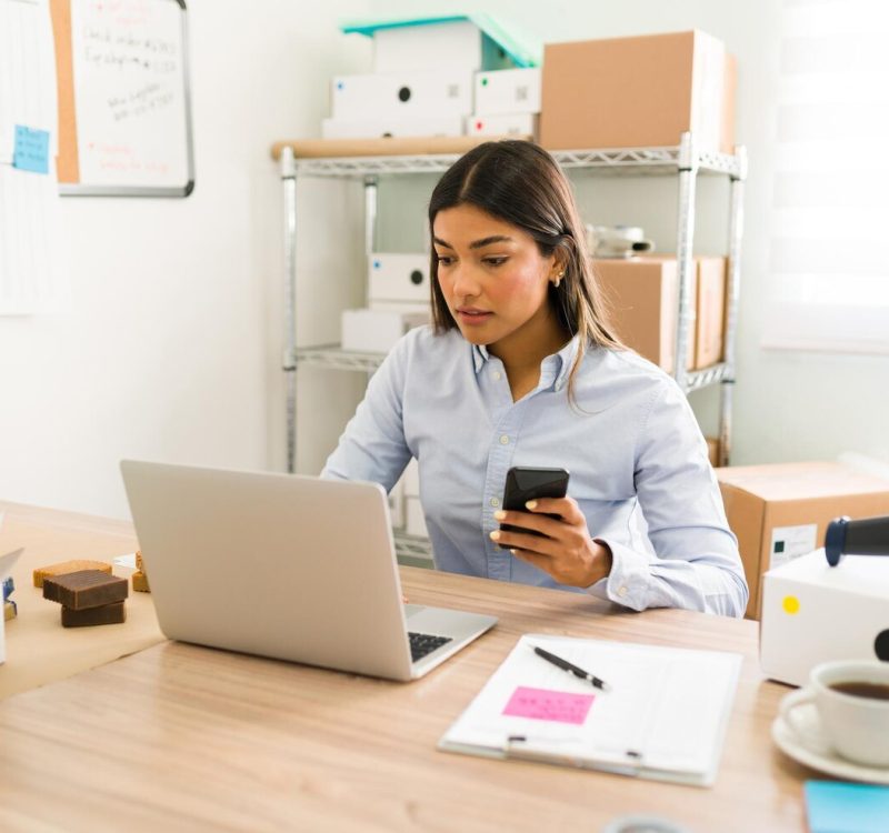 hispanic-young-woman-her-office-looking-her-laptop-smartphone-check-customers-orders-her-online-beauty-shop_662251-1876